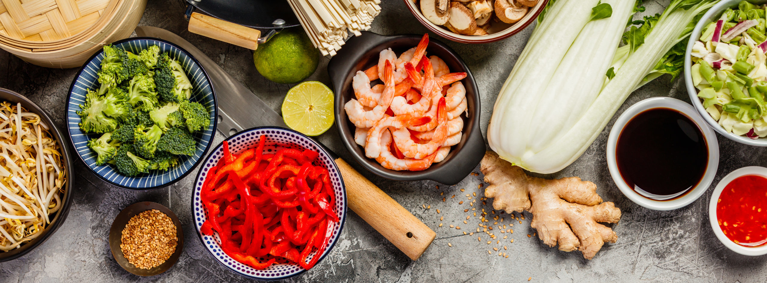Asian cuisine ingredients on grey stone background, top view. Vegetables, spices, shrimp, noodles, sauces for cooking vietnamese, thai or chinese food. Clean eating food concept